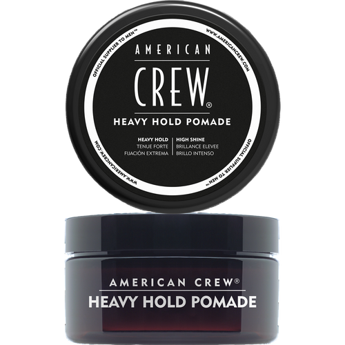 Translucent dark amber jar labeled American Crew Heavy Hold Pomade with its black lid removed and displayed above it, on a light grey backdrop.
