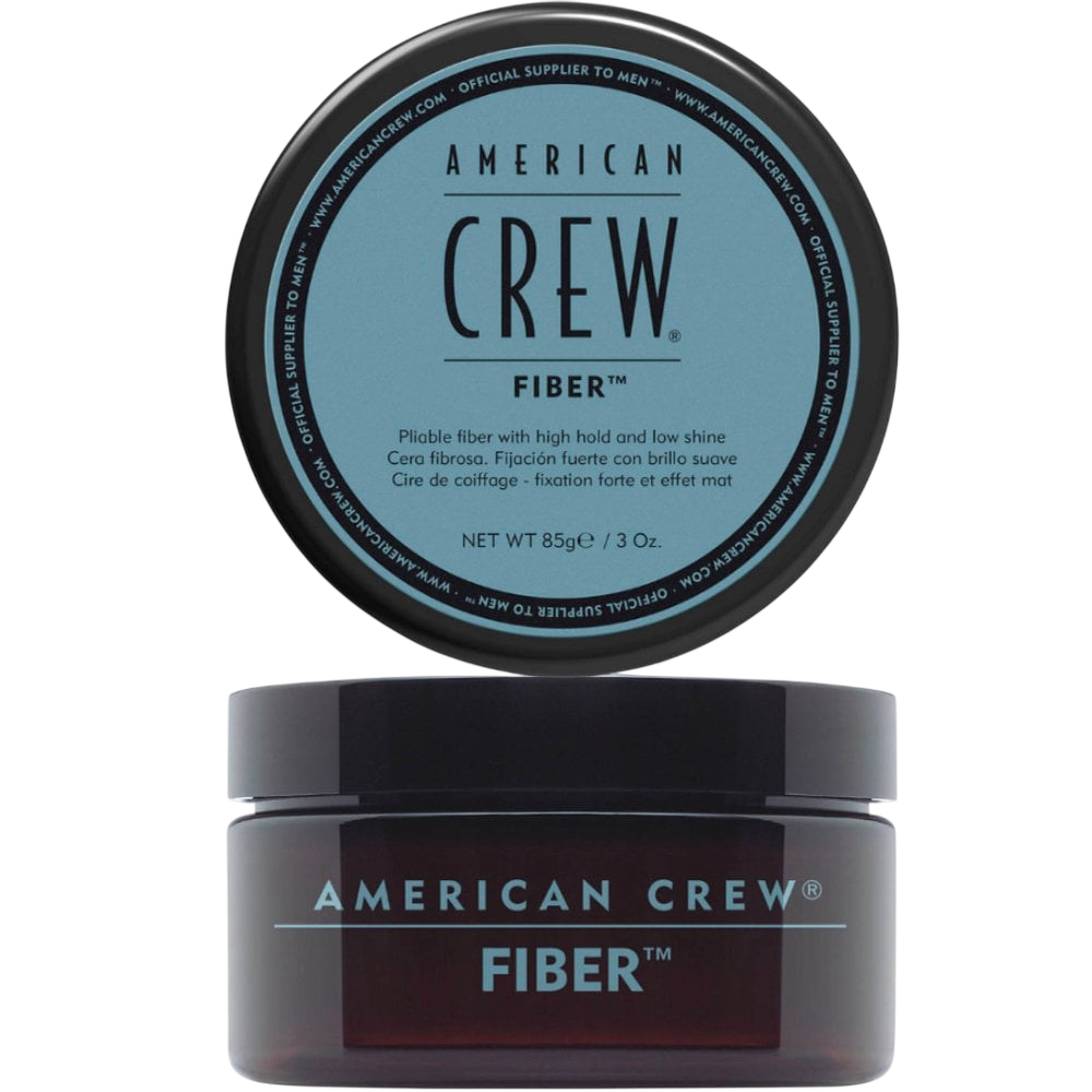 Translucent amber jar labeled American Crew Fiber with a black lid, light blue label text, lid displayed above the open jar, on a light grey backdrop.