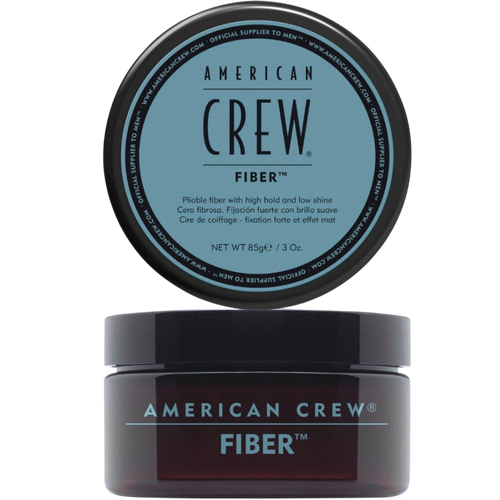 Translucent amber jar labeled American Crew Fiber with a black lid, light blue label text, lid displayed above the open jar, on a light grey backdrop.