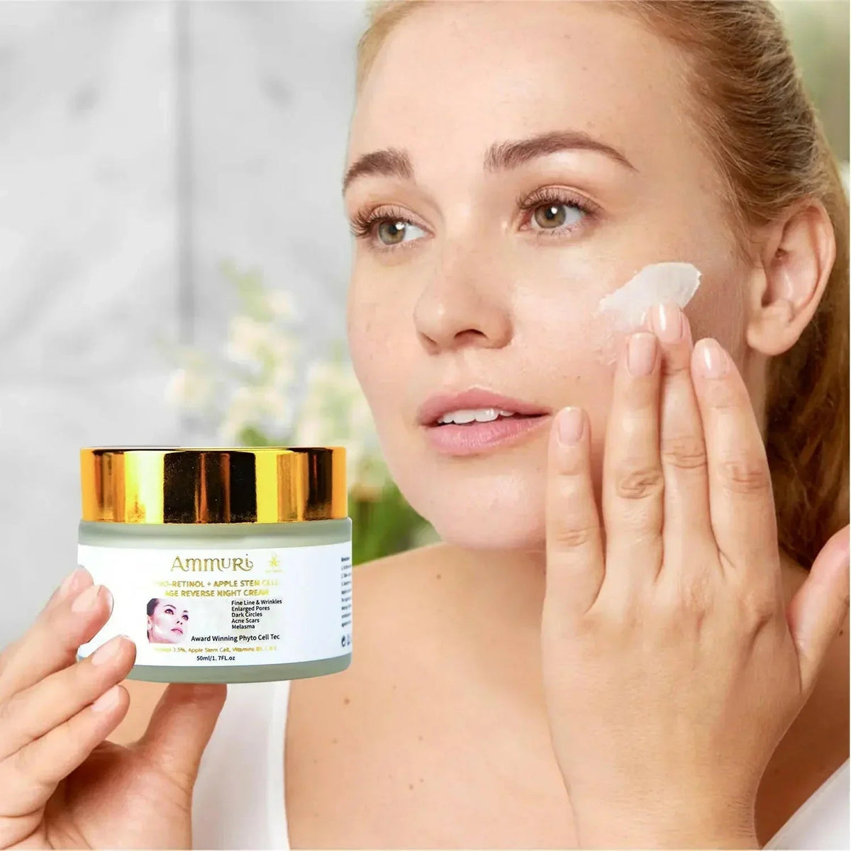 Woman applying Ammuri Apple Stem Cell Anti-Ageing Cream to her cheek while holding the jar