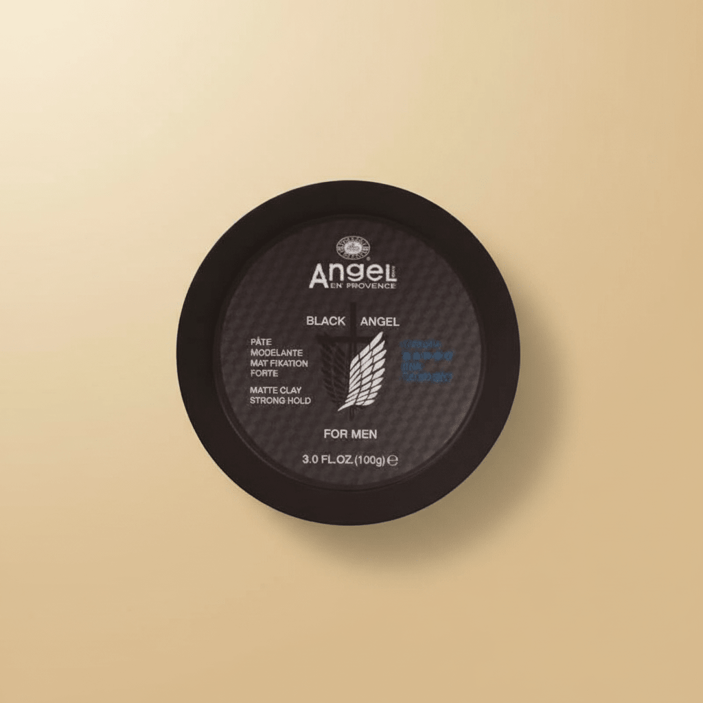 Round black tin lid viewed from above, labeled "Angel En Provence, Black Angel, Matte Clay Strong Hold, For Men, 3.0 FL.OZ. (100g)", on a tan background.